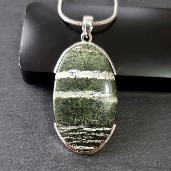 Green Swiss Opal gemstone displaying rich green colouring with shimmering iridescent white veining and a polished finish.