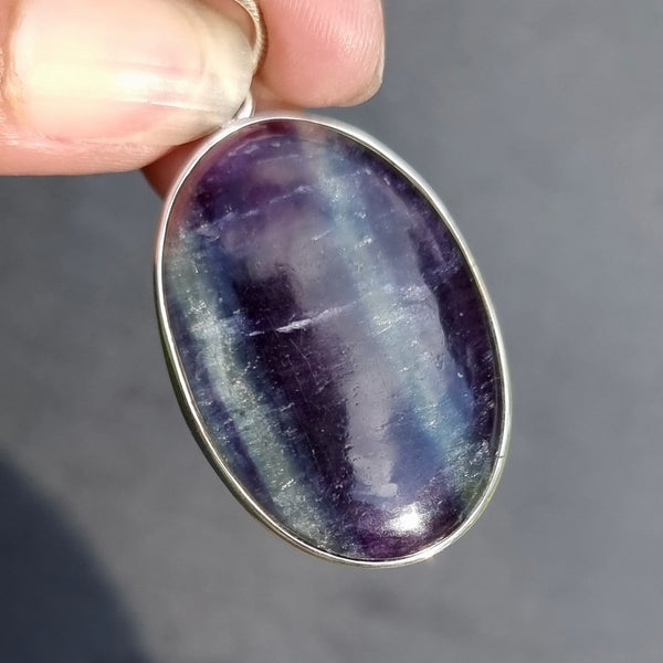 Natural Fluorite gemstone displaying beautiful purple and green banding with a polished finish and distinctive colour zoning.